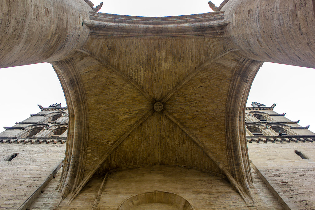 Vista desde abajo del arco gótico de la catedral de Montpellier con detalles arquitectónicos y gárgolas.