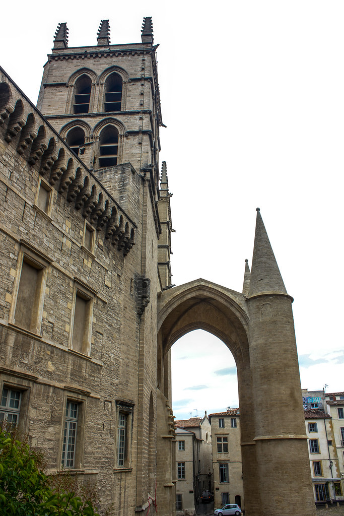 Arquitectura gótica de la catedral de Montpellier con el campanario y el arco característico en un día nublado.