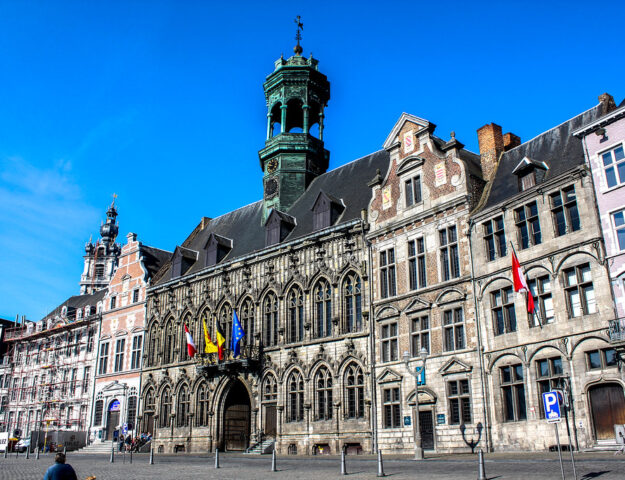 Fachada del ayuntamiento gótico con banderas en Mons, Bélgica.