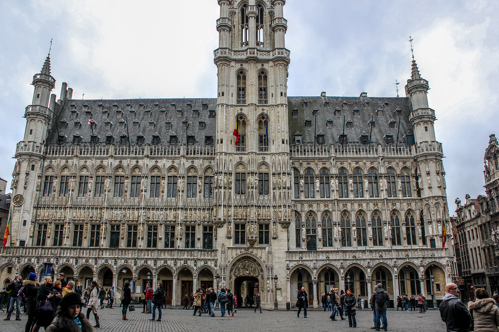 Turistas caminando frente al Ayuntamiento de Bruselas en la Grand Place.