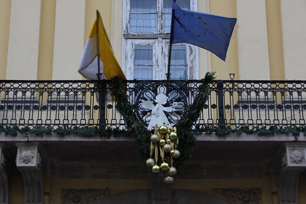 Balcón decorado con banderas y adornos navideños en Székesfehérvár.