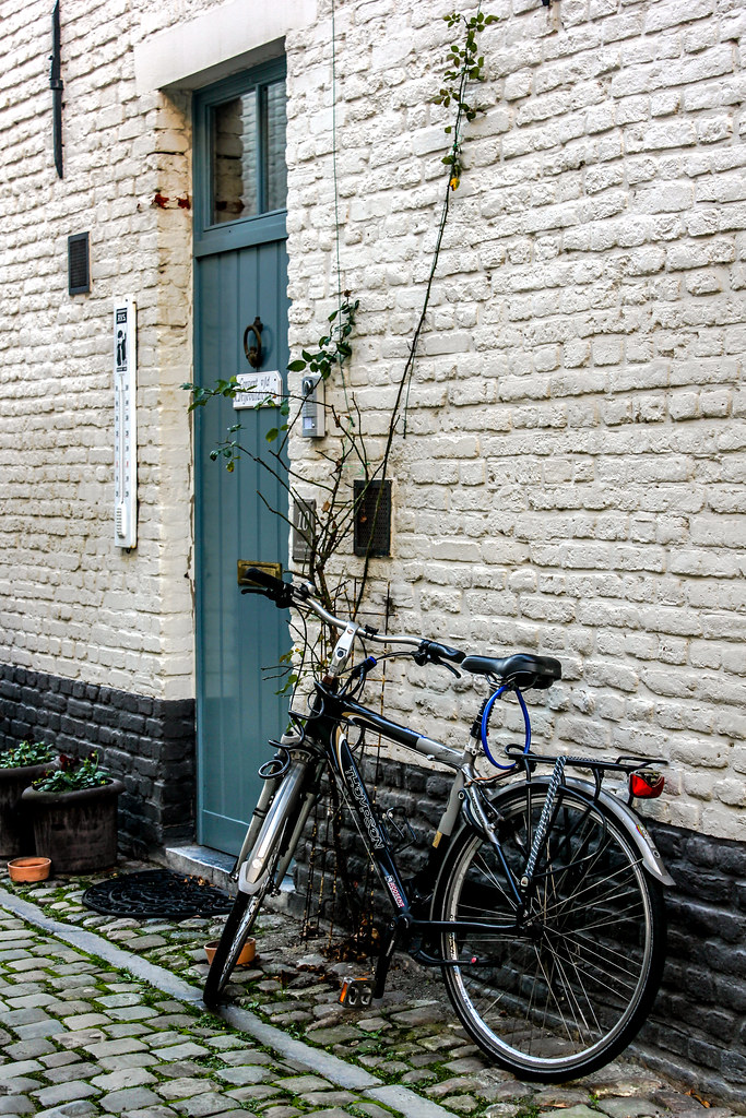 Bicicleta apoyada contra la pared de ladrillo pintado de blanco en el Klein Begijnhof de Lovaina.