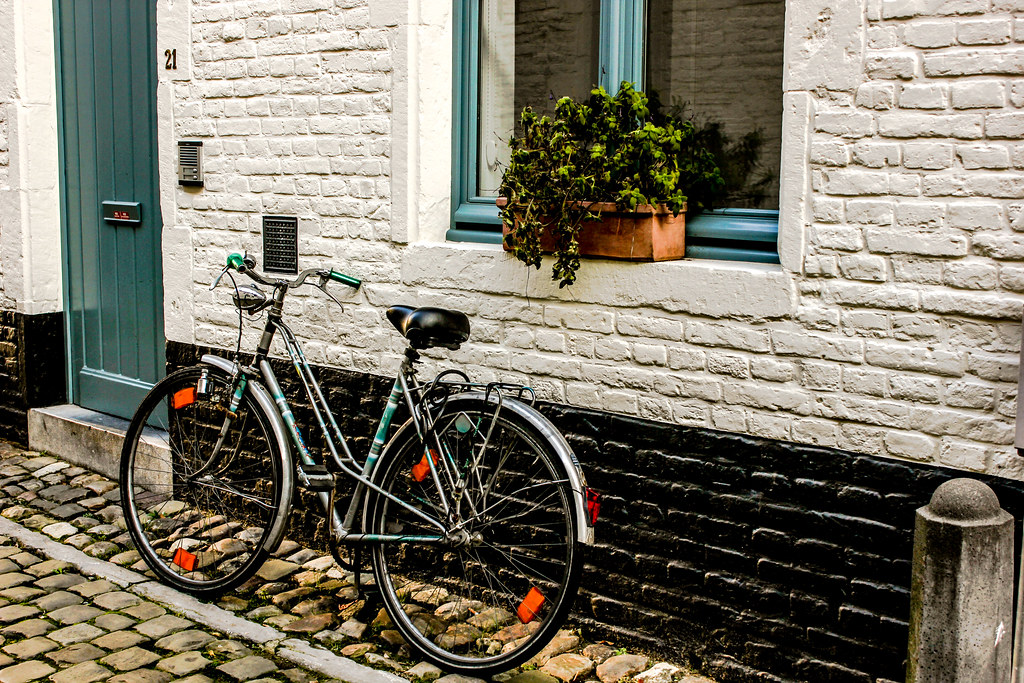Bicicleta estacionada en el histórico Klein Begijnhof con casas de ladrillo blanco en Lovaina.