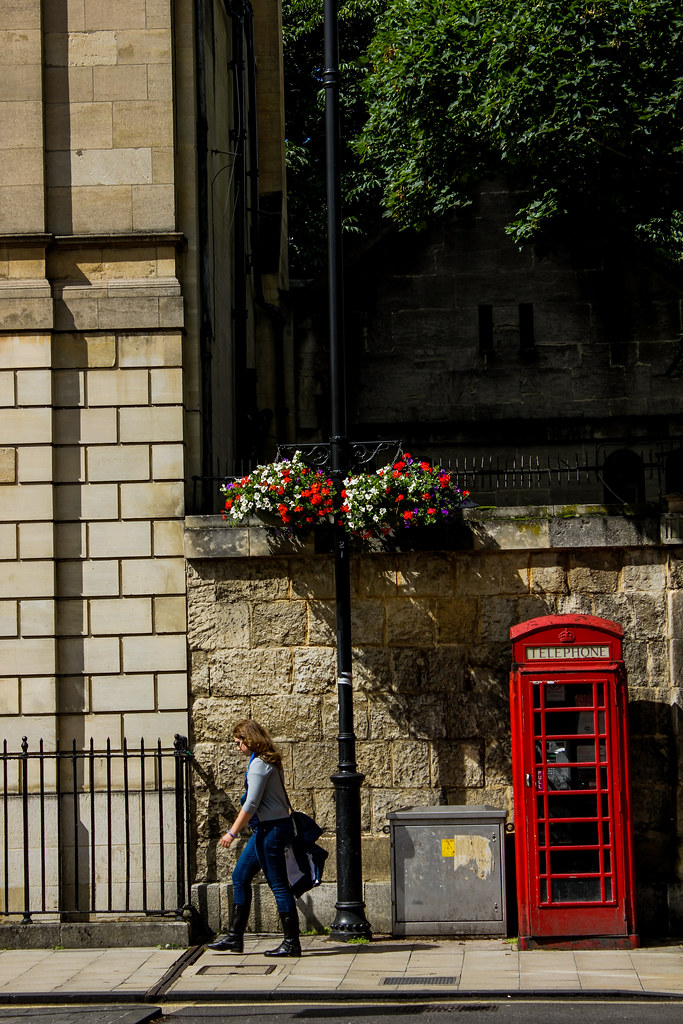 Cabina telefónica roja tradicional en Oxford con mujer pasando.