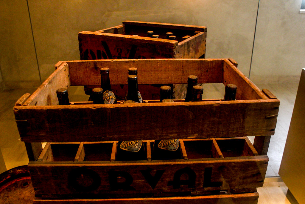 Cajas de madera antiguas de cerveza Orval con botellas en interior de museo.