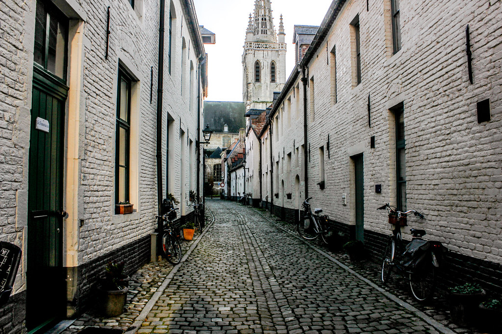 Calle empedrada del Klein Begijnhof con casas tradicionales y bicicletas en Lovaina, Bélgica.