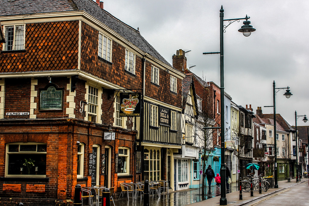 Calle histórica con edificios de época en Canterbury en día lluvioso.