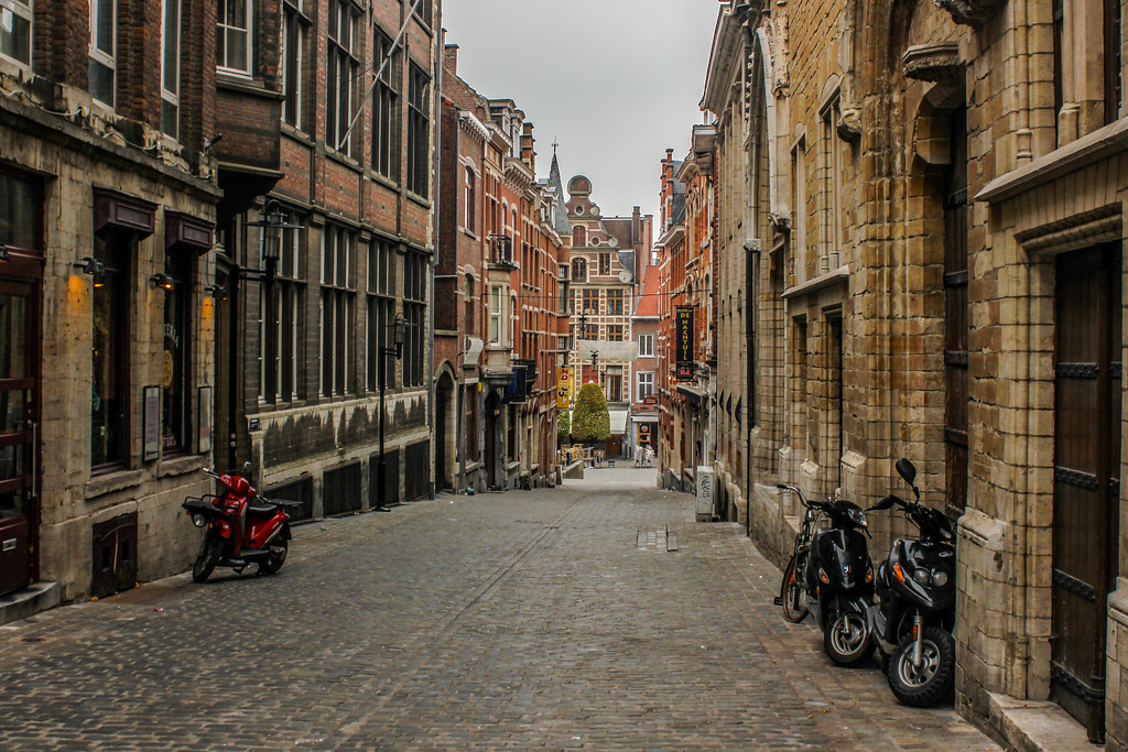 Calle Zeelstraat de Lovaina con edificios históricos y motocicletas estacionadas.