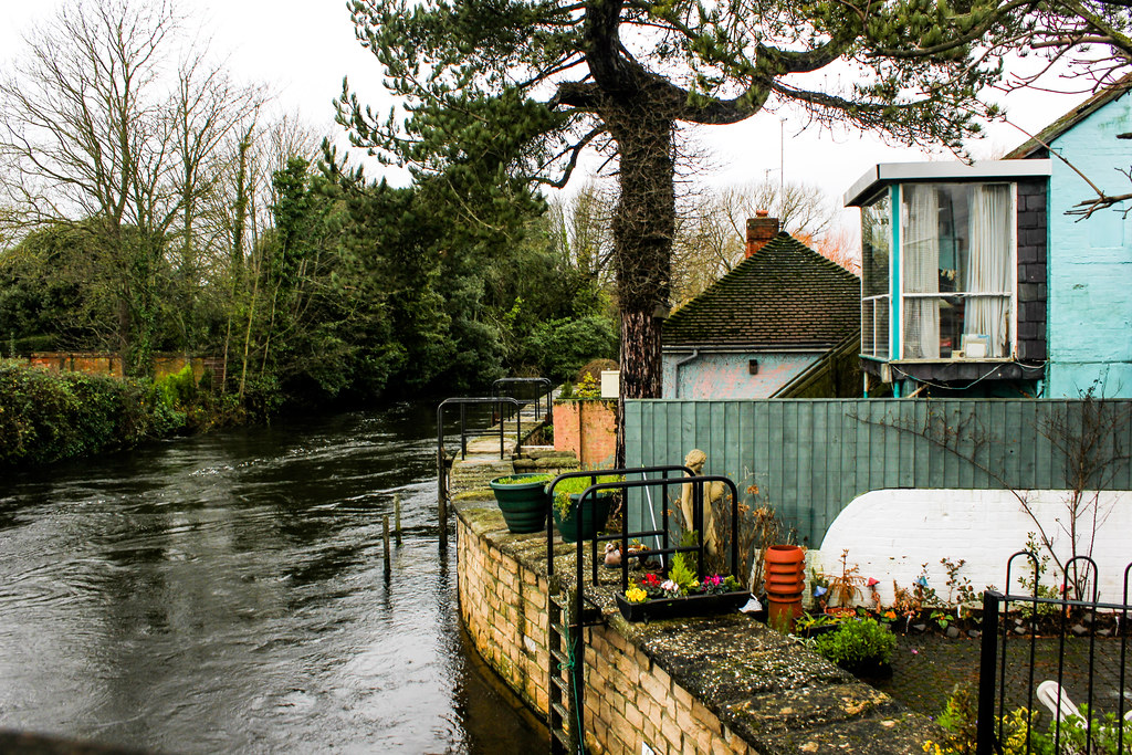 Casa junto al río con jardín en Christchurch, Dorset, en día nublado.