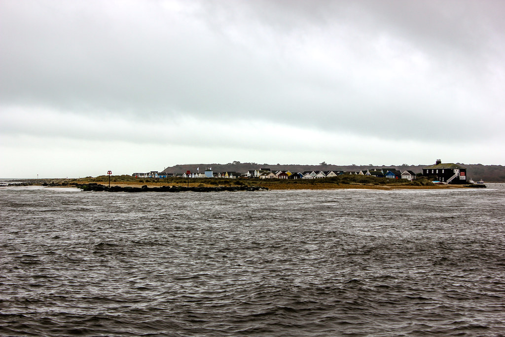 Casas en Mudeford Sandbank frente al mar agitado en un día nublado.
