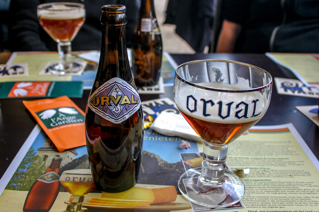 Cerveza Orval servida en copa con botella y posavasos en mesa de cata.