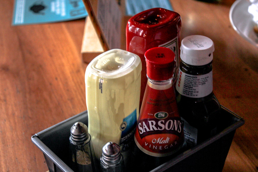 Condimentos típicos británicos en mesa de pub con vinagre Sarson's.