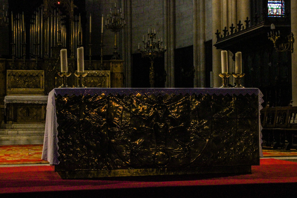 Detalle del altar tallado en la catedral de Montpellier con candelabros y el órgano de fondo.