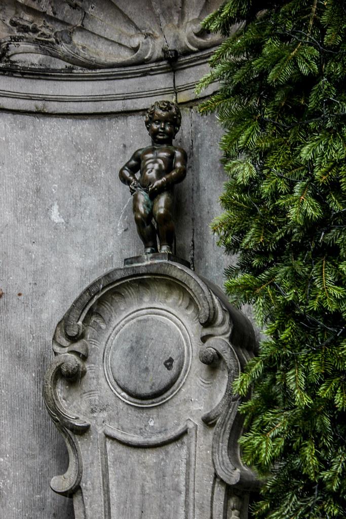 Detalle de la estatua Manneken Pis en primer plano con hiedra.