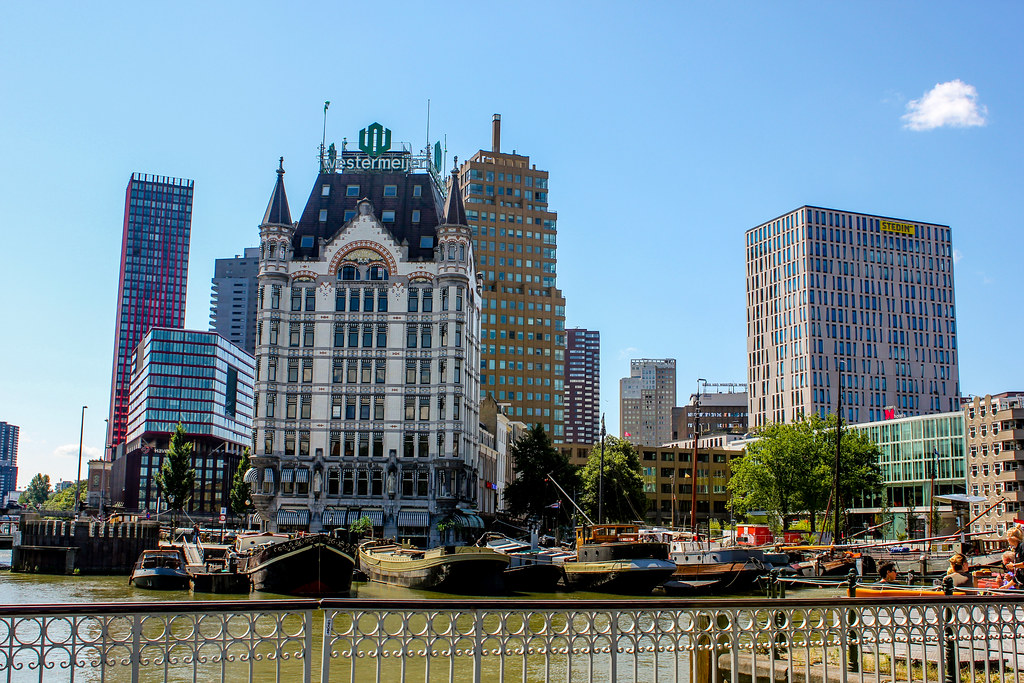 Edificio histórico Witte Huis frente al río Maas en Rotterdam con barcos y rascacielos modernos.