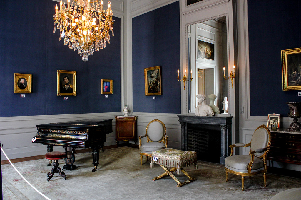 Elegante sala de música con piano de cola, candelabro de cristal y retratos en el Palacio Real, Bruselas.