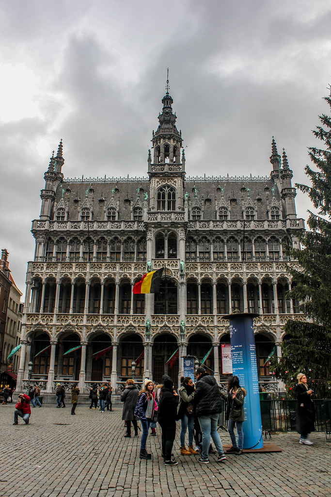 Visitantes en la entrada del Museo de la Ciudad de Bruselas en la Grand Place, con bandera belga.