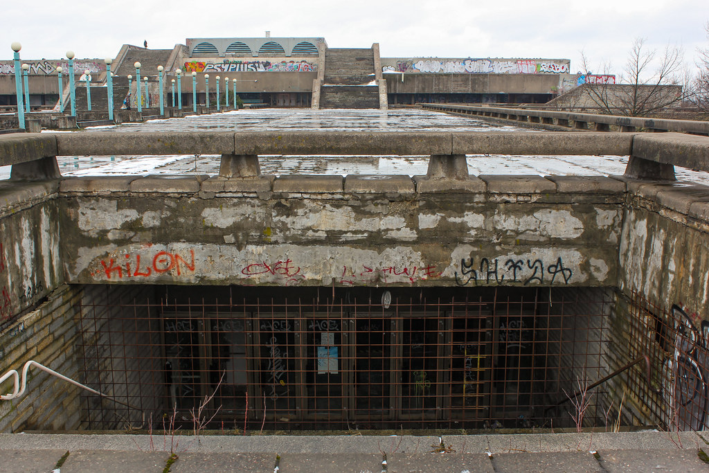 Entrada subterránea cerrada con rejas en Linnahall, Tallin, con grafitis.