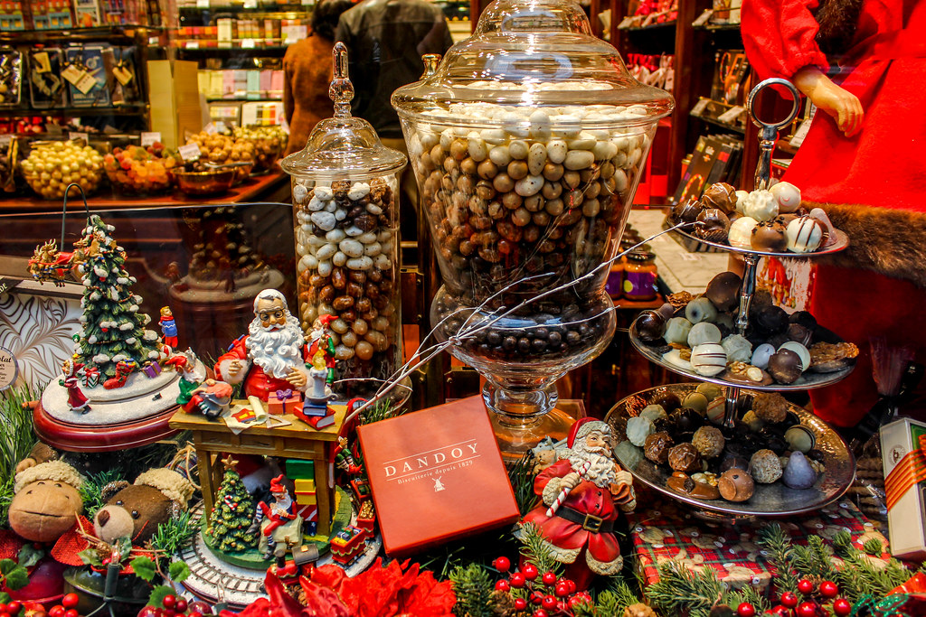 Escaparate navideño con dulces variados, figuras de Santa Claus y decoraciones festivas.
