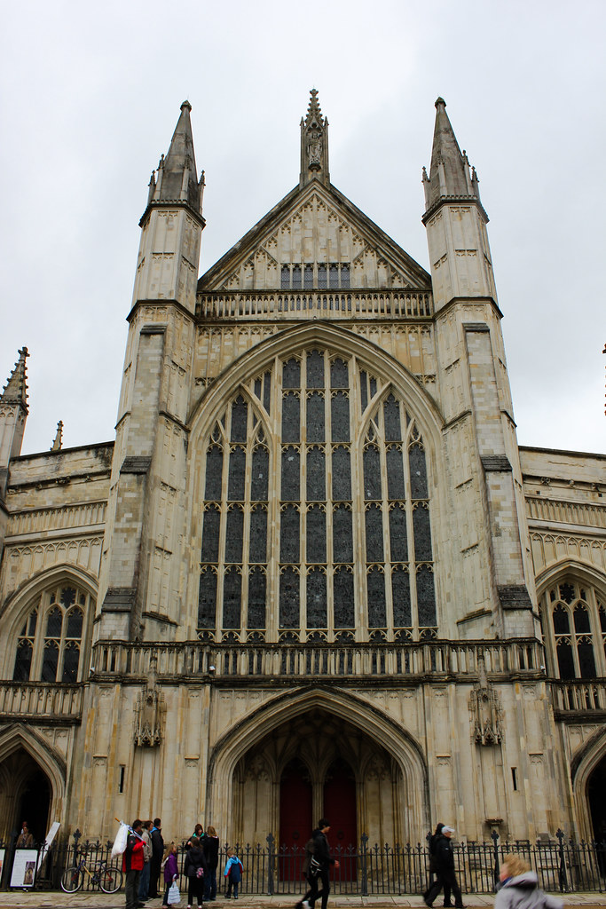Fachada principal de la Catedral de Winchester con visitantes en la entrada.