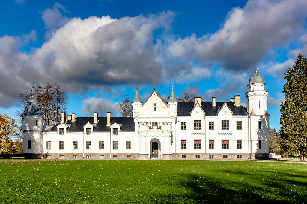 Fachada del histórico Palacio Alatskivi bajo un cielo azul con nubes en Estonia.