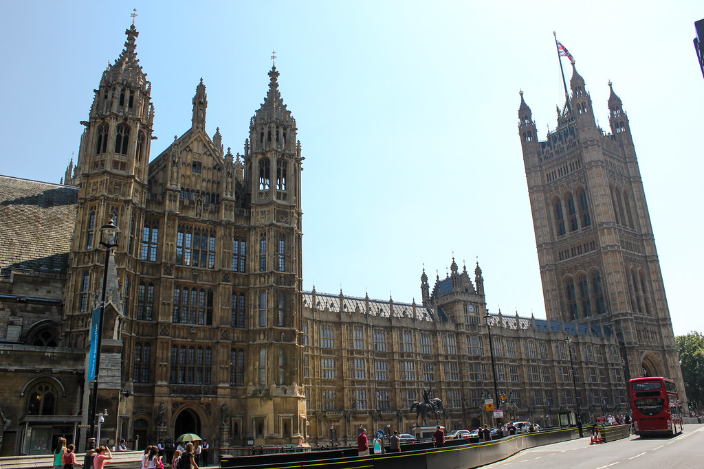 Fachada del Palacio de Westminster con la Torre Victoria y un autobús de dos pisos en Londres.
