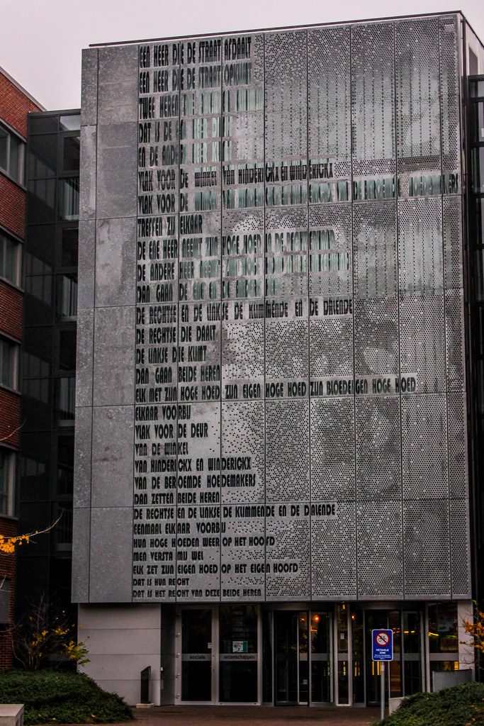 Fachada de la Facultad de Ciencias Sociales, Universidad de Lovaina, con poema en la pared.