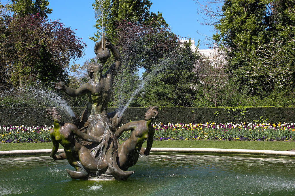 Fuente con escultura de tritones en Regent's Park, con tulipanes coloridos al fondo.