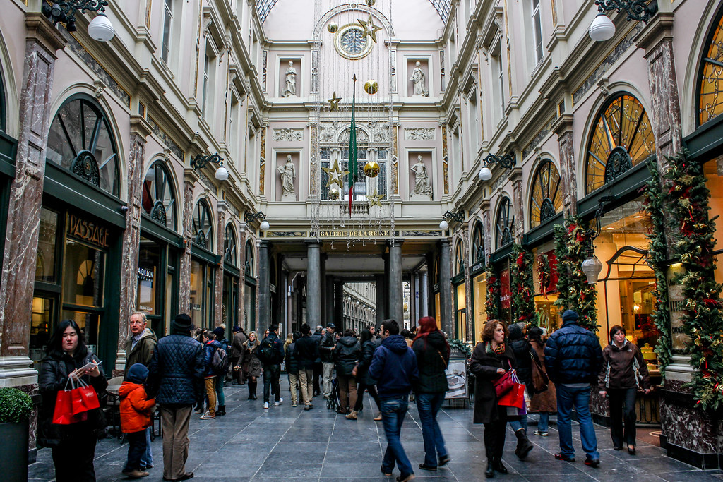 Gente paseando por las Galerías Saint-Hubert adornadas en Bruselas durante temporada navideña.