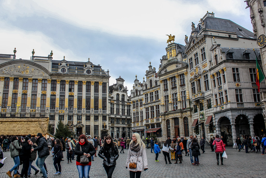 Gente paseando por la Grand Place de Bruselas con edificios históricos de fondo.