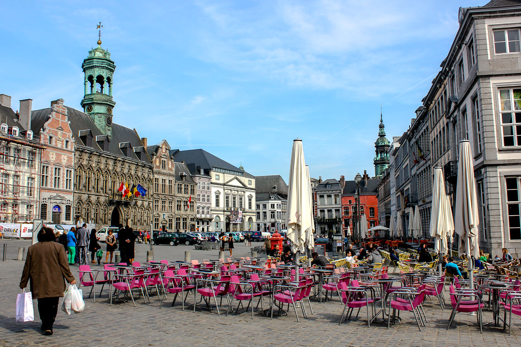 Grand Place de Mons con terraza de café al aire libre y arquitectura clásica belga de fondo.
