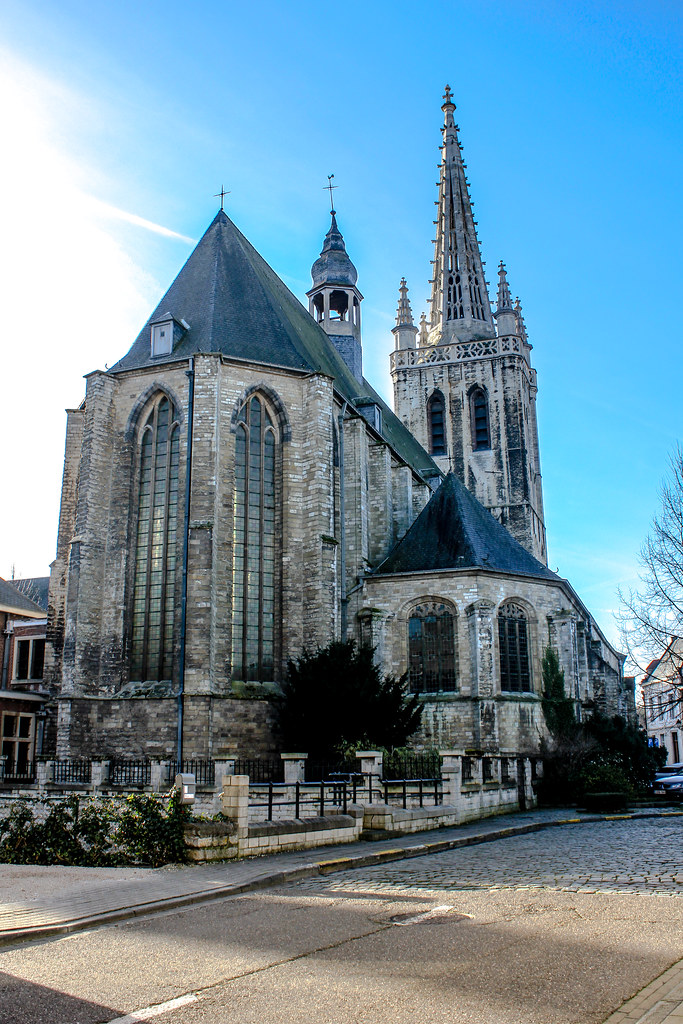 Iglesia de Santa Gertrudis en Lovaina con su característico campanario puntiagudo y cielo azul.