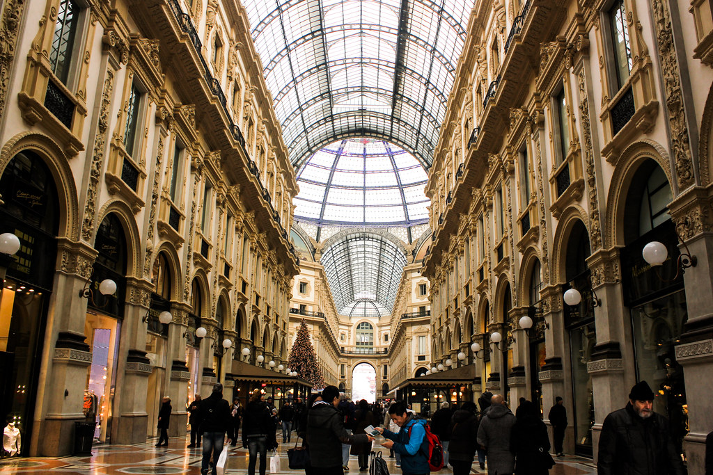 Interior de la Galleria Vittorio Emanuele II en Milán con visitantes y arquitectura ornamentada.