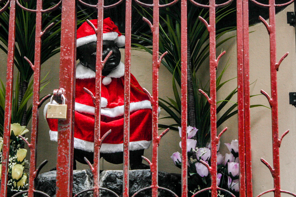 Estatua de Janneken Pis vestida de Santa Claus detrás de una verja roja en Bruselas durante la temporada navideña.