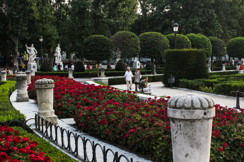 Jardines de la Plaza de Oriente con esculturas y flores.