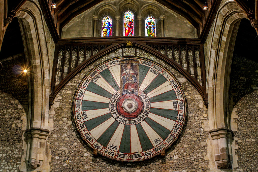 Mesa Redonda del Rey Arturo en el Gran Salón de Winchester con vitrales al fondo.