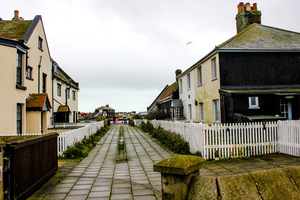 Camino en Mudeford Quay con casas tradicionales y valla blanca.
