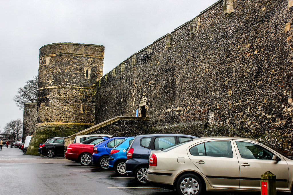 Muralla medieval de Canterbury con coches estacionados al frente.