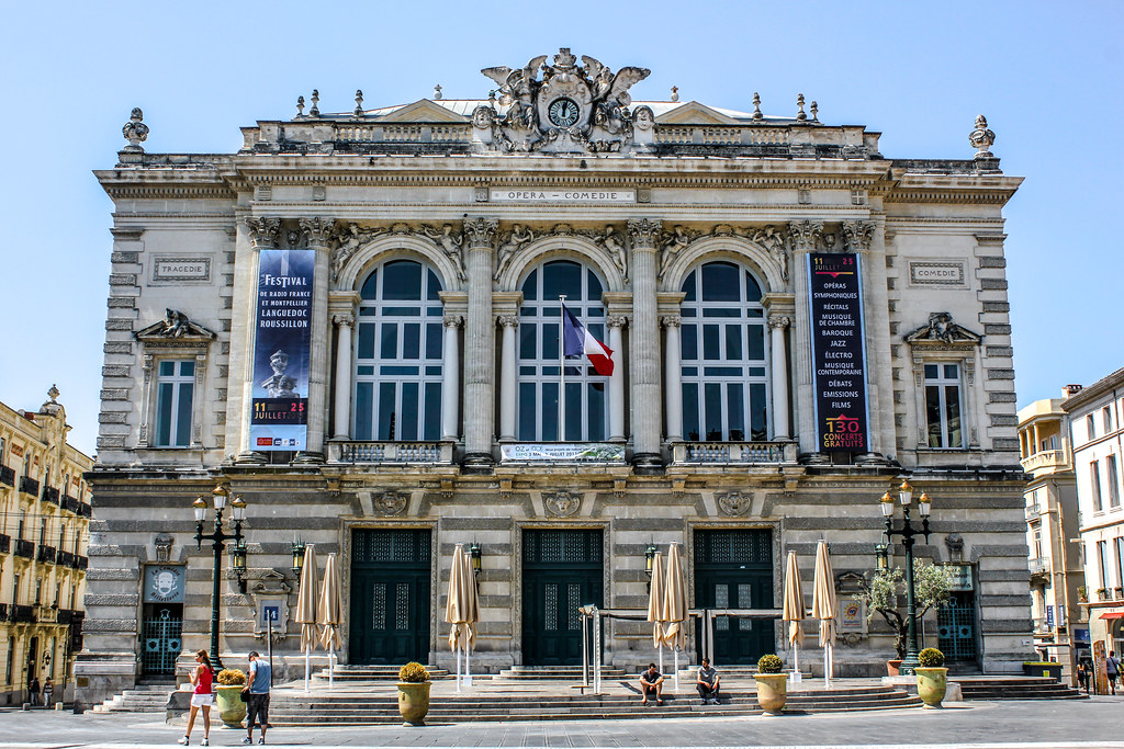 Fachada del Ópera Comédie con carteles de festivales en Montpellier en un día soleado.