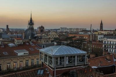 Vista panorámica al atardecer de Toulouse con tejados y torres históricas.