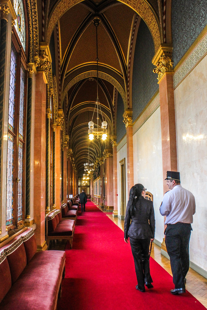 Pasillo largo con alfombra roja y arcos góticos en el Parlamento de Budapest.