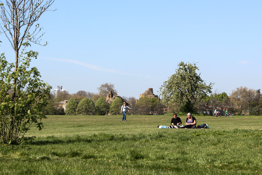 Personas disfrutando de un picnic en el césped de Regent's Park con vistas al skyline de Londres en la distancia.