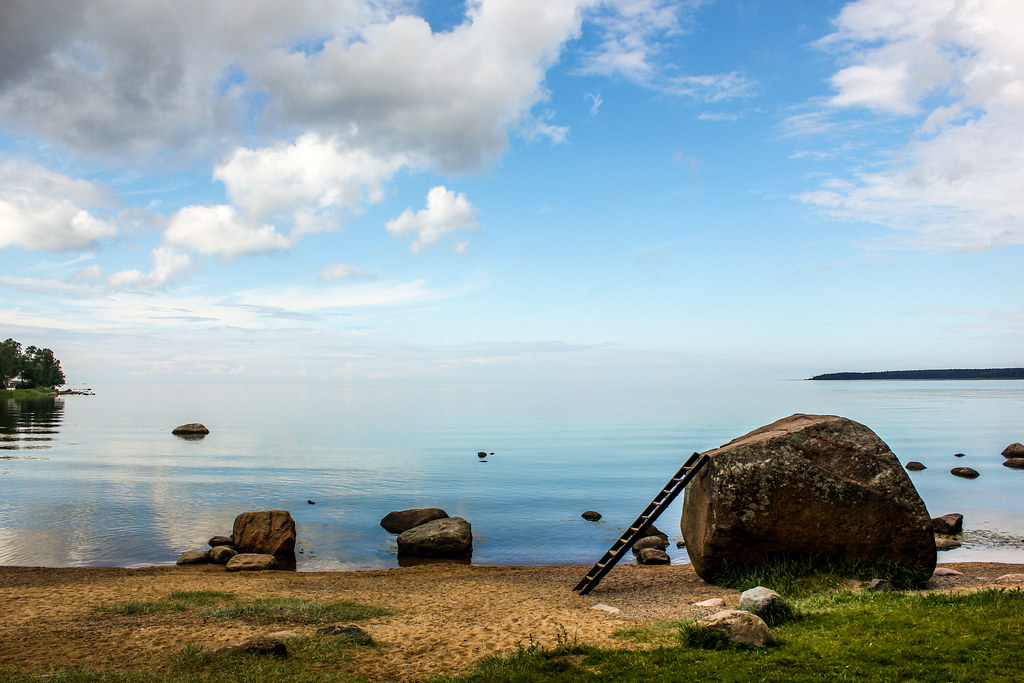 Playa serena en Käsmu, Estonia, con rocas y reflejos en las aguas calmas del Mar Báltico.