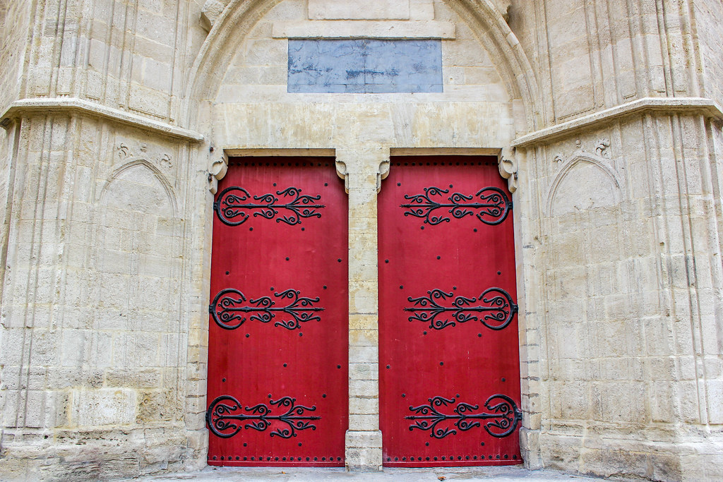 Puertas rojas con adornos de hierro forjado en la entrada de la catedral de Montpellier.