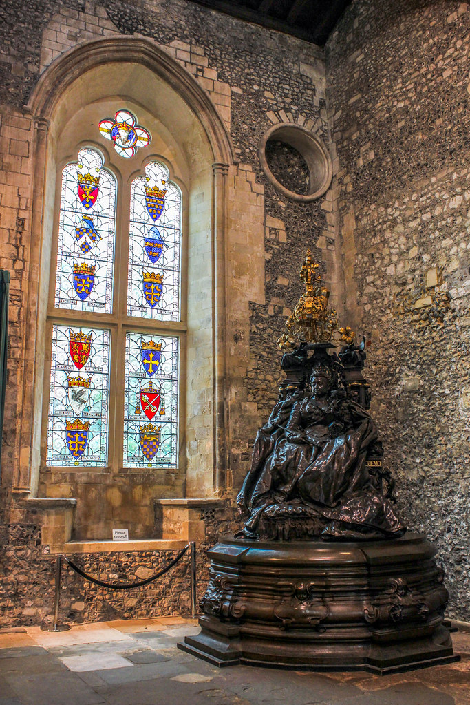Estatua de la reina Victoria en el Gran Salón de Winchester con vitrales heráldicos.