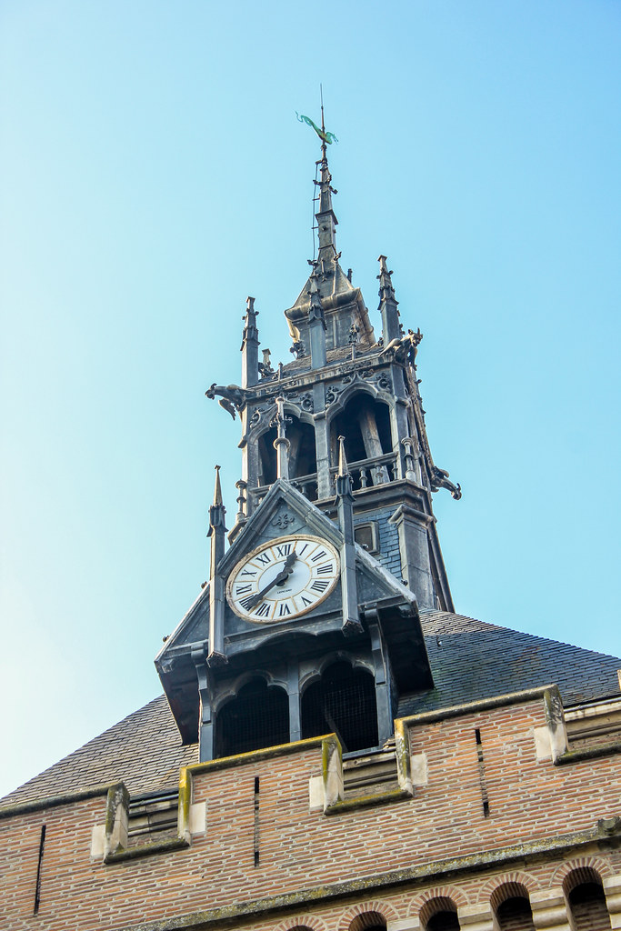 Reloj de la torre del Donjon du Capitole bajo un cielo azul en Toulouse.