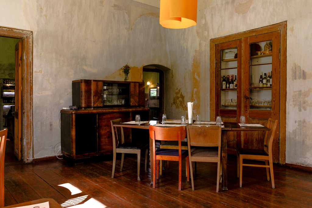 Interior rústico del Restaurante Põhjaka en Estonia, con muebles de madera y paredes de textura desgastada.