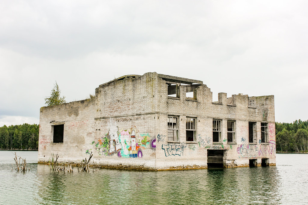 Ruinas parcialmente sumergidas con grafiti en el lago de la cantera de Rummu, Estonia, en un día nublado.
