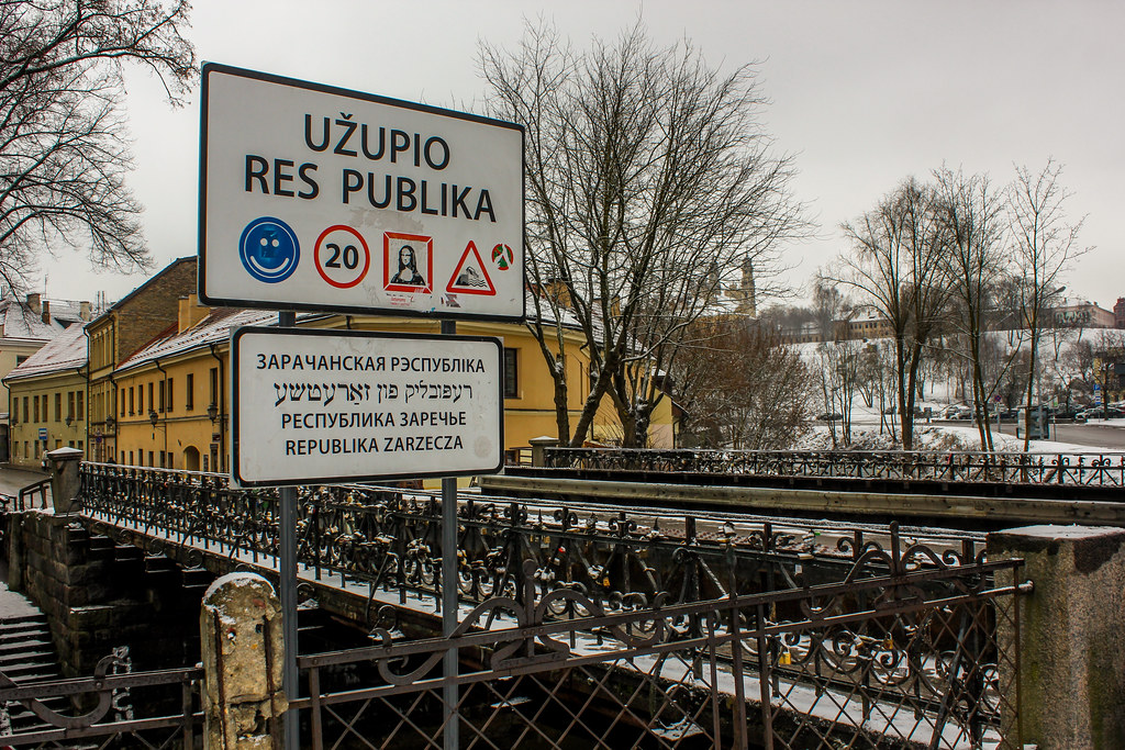 Señal de bienvenida a la República de Užupis en varios idiomas con puente y nieve, Vilna, Lituania.