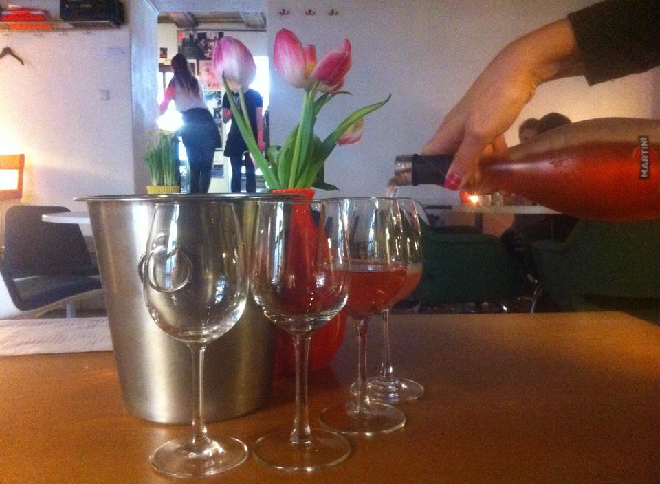 Servicio de vino rosado en elegantes copas con un cubo de hielo y tulipanes en el Kohvik Must Puudel.